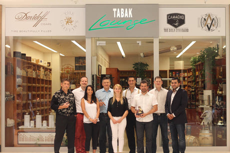Team der Tabaklounge Frankfurt vor dem Ladengeschäft mit Zigarrenregalen
