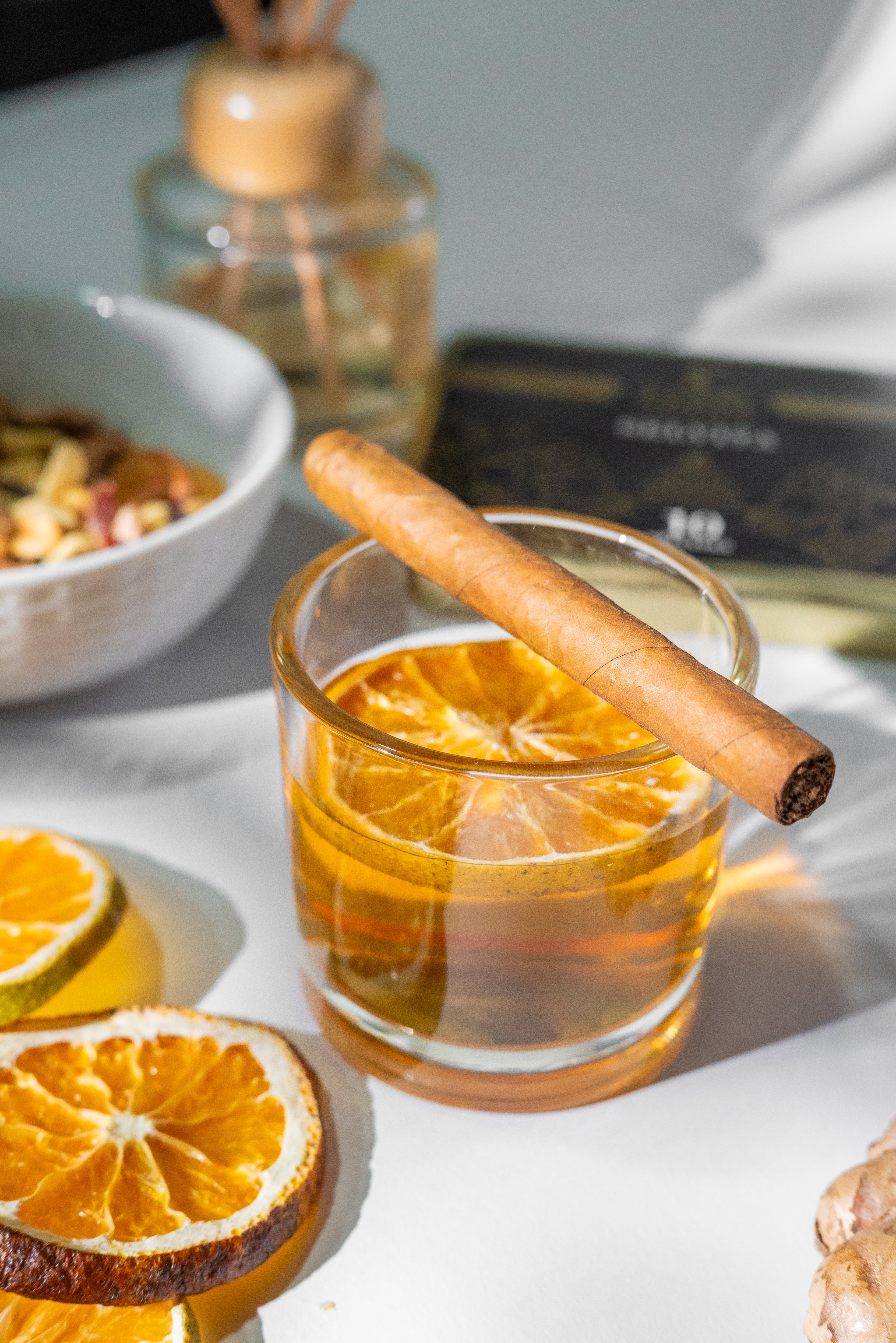 Zigarillo auf Orangencocktail mit getrockneter Scheibe, Nüsse im Hintergrund